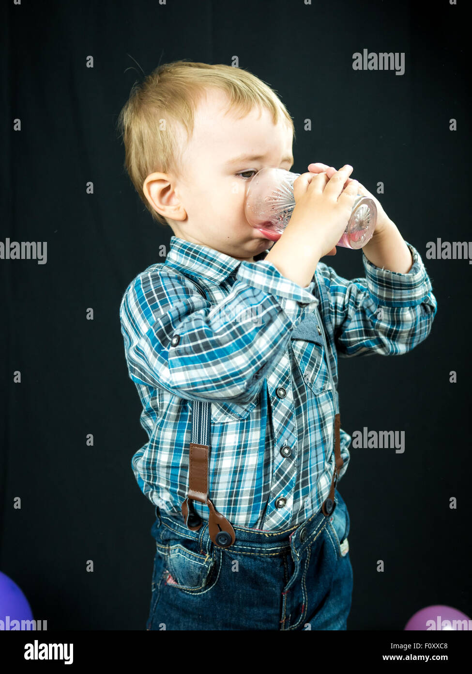 kid boy drinking juice. Studio photo with black background Stock Photo