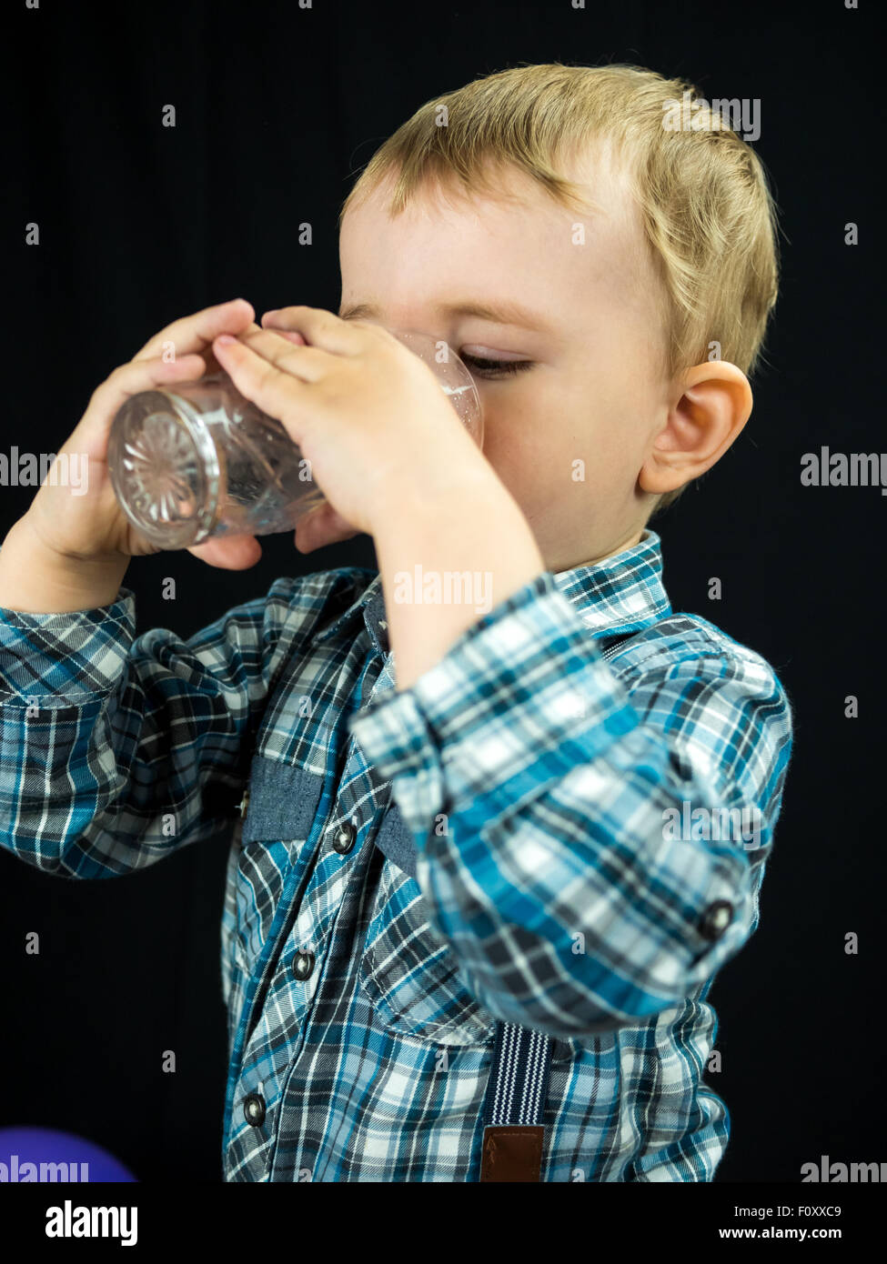 kid boy drinking juice. Studio photo with black background Stock Photo