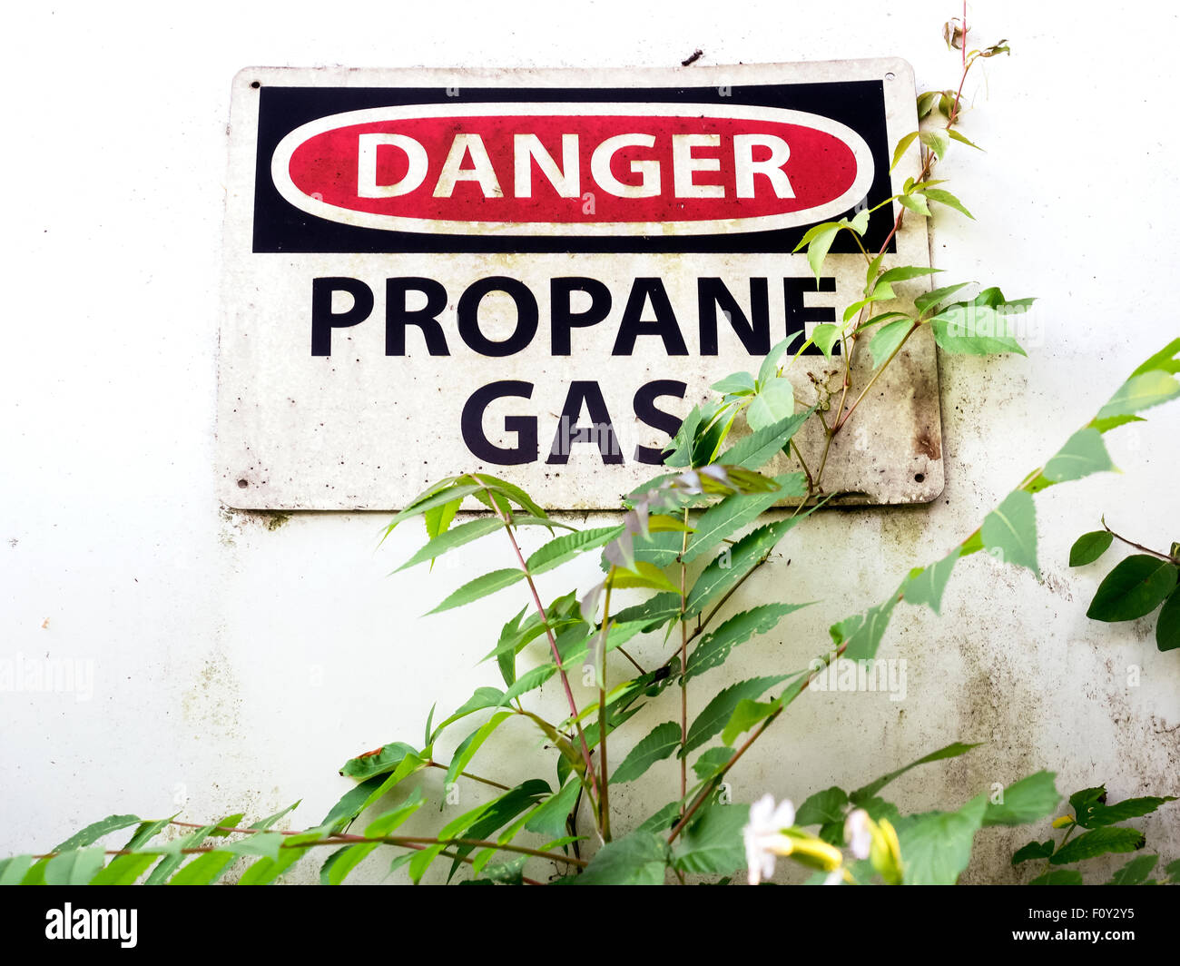 Dirty ‘Danger” sign on propane gas tank in rural area Stock Photo