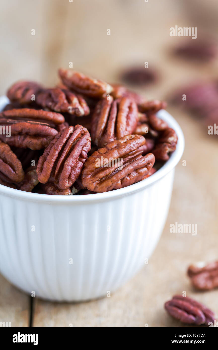 Raw Pecan in a white bowl on wooden board Stock Photo