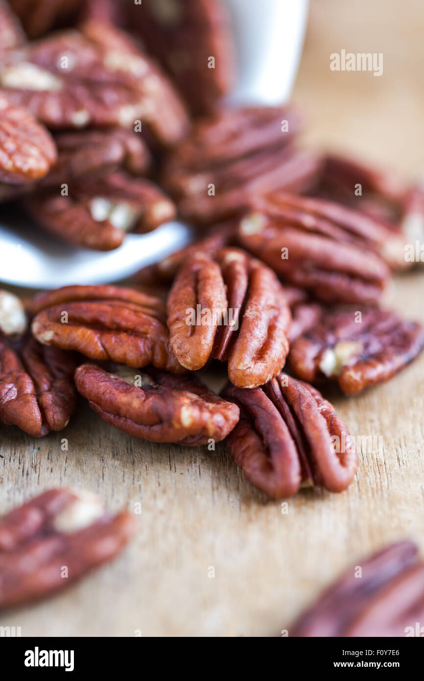 Raw Pecan in a white bowl on wooden board Stock Photo
