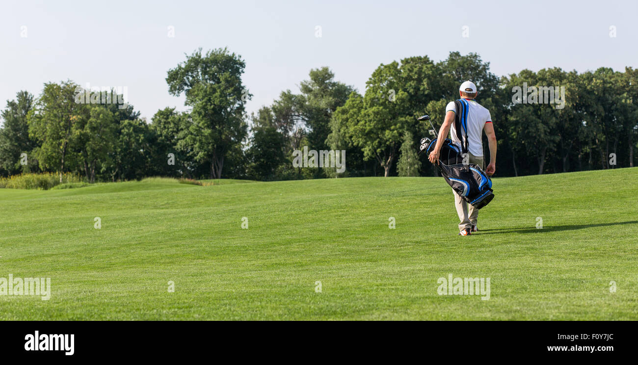 Golfer with golf bag walking down the course. Man going to spend his