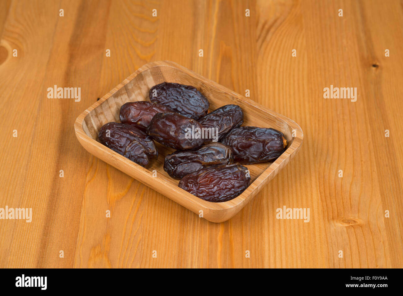 Bowl of dried dates on a wooden background Stock Photo - Alamy