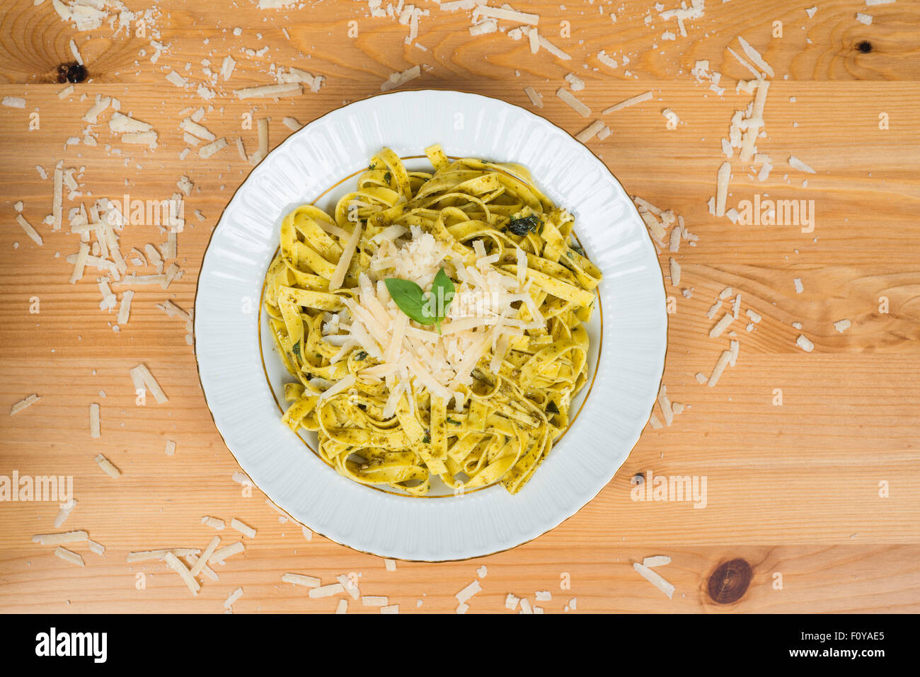 Tagliatelle pasta with pesto sauce and basil leafs on white plate, wood background Stock Photo