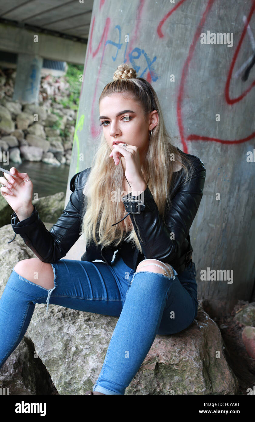 tough looking teenage girl with her nose pierced smoking a cigarette Stock Photo