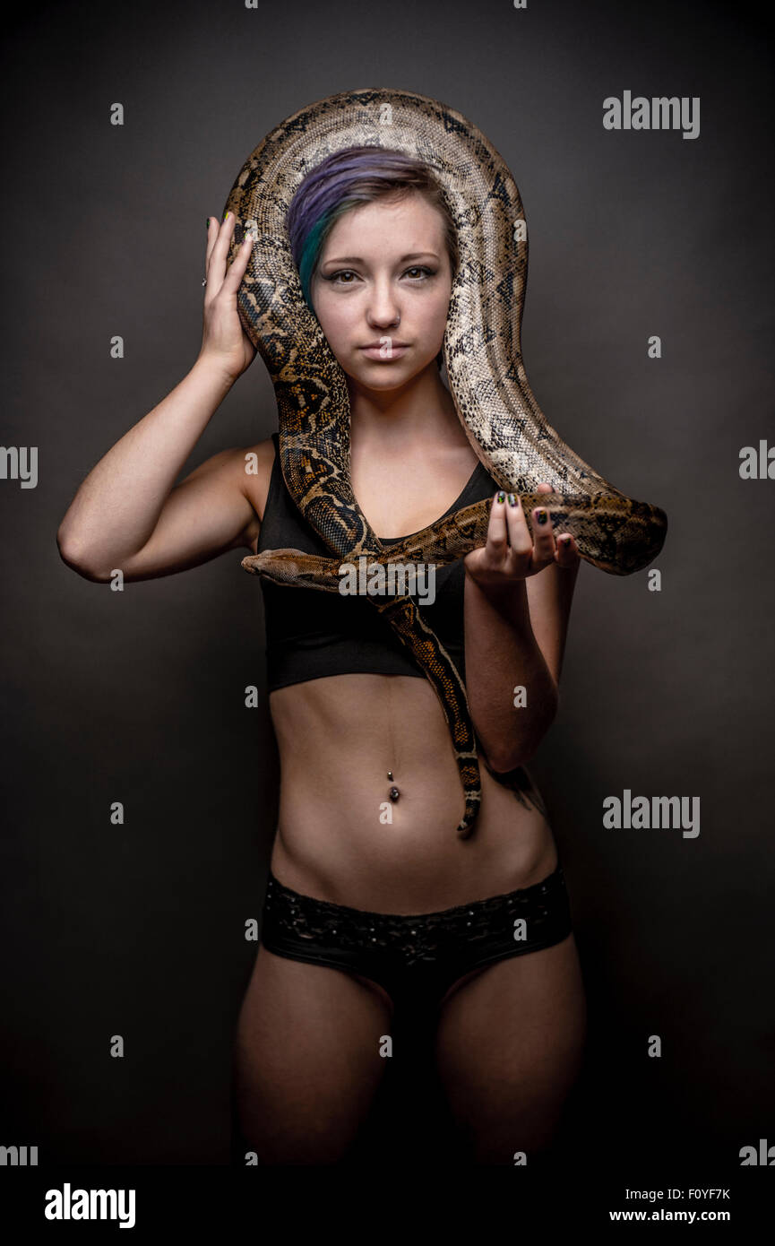 A young woman girl female person posing with a python  snake wrapped around her head  , UK (not suffering from ophiophobia - the fear of snakes) Stock Photo