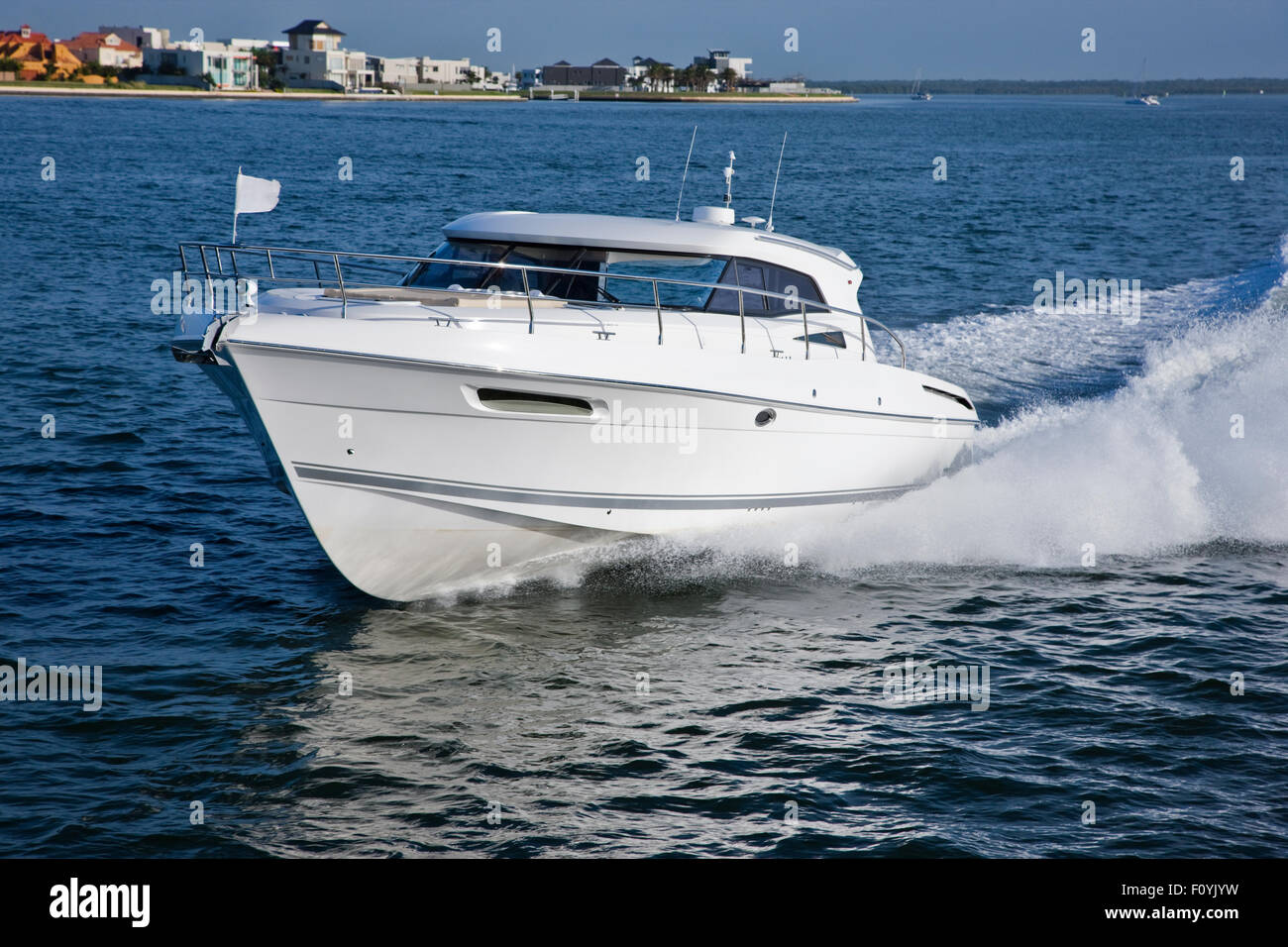 Image of an elegant boat sailing in front of a coast with small houses Stock Photo