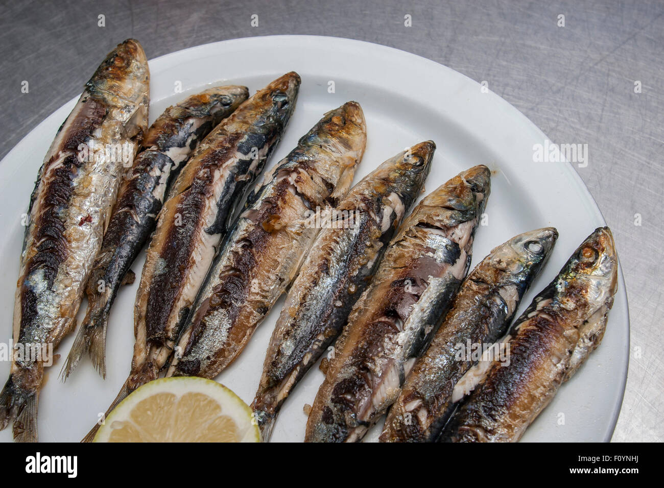fried sardines served with lemon on white plate Stock Photo Alamy
