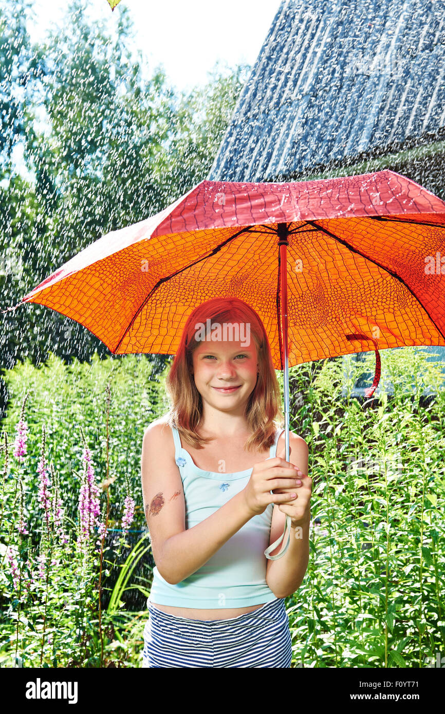 Happy girl with red umbrella under summer rain Stock Photo