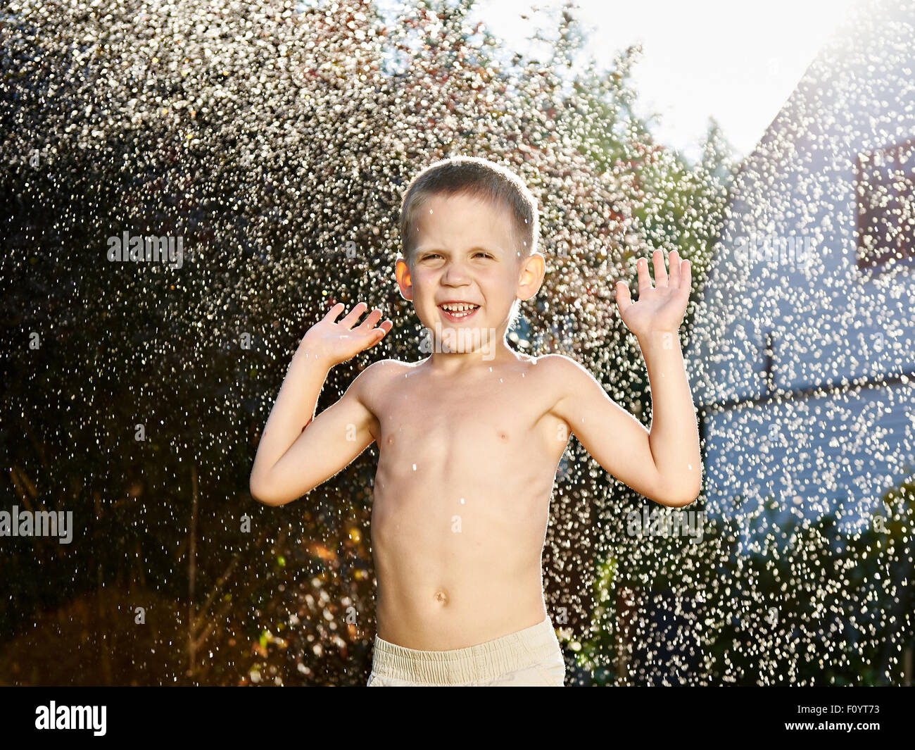 Happy little boy under summer rain Stock Photo