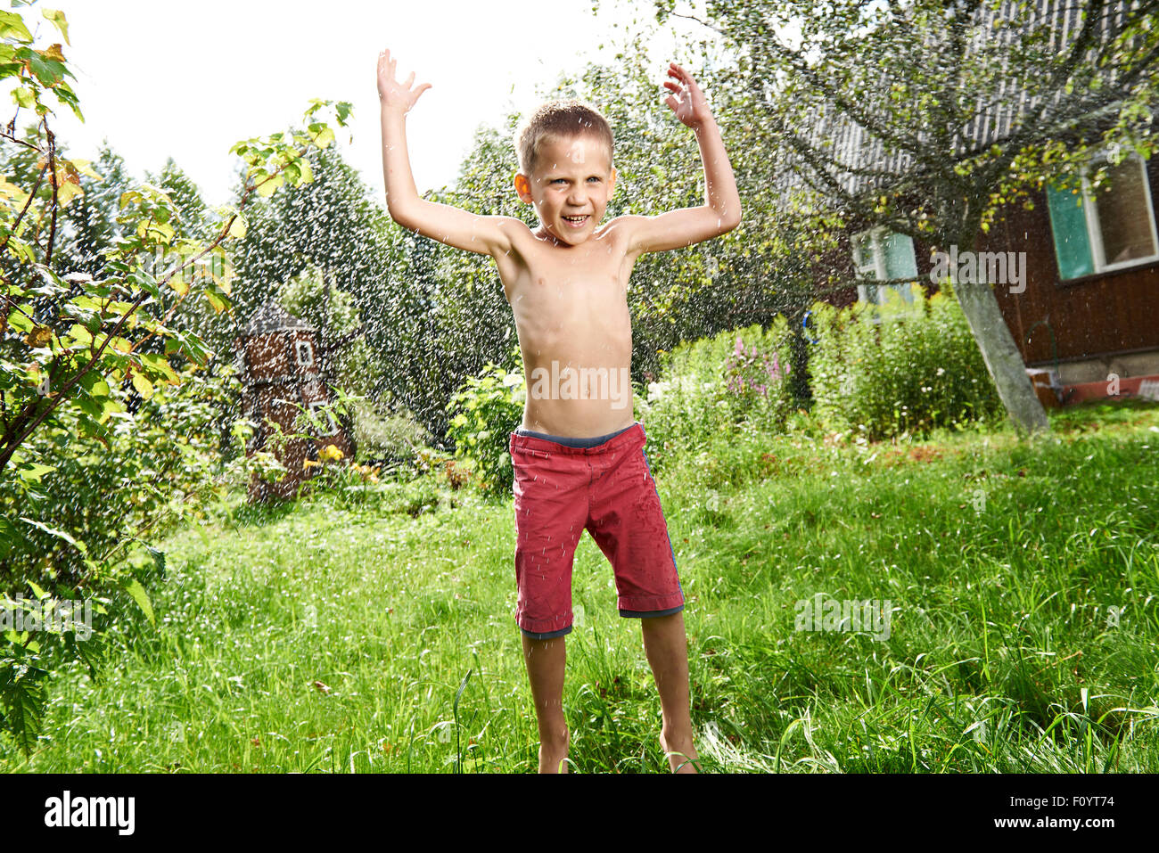 Happy little boy is jumping under summer rain Stock Photo