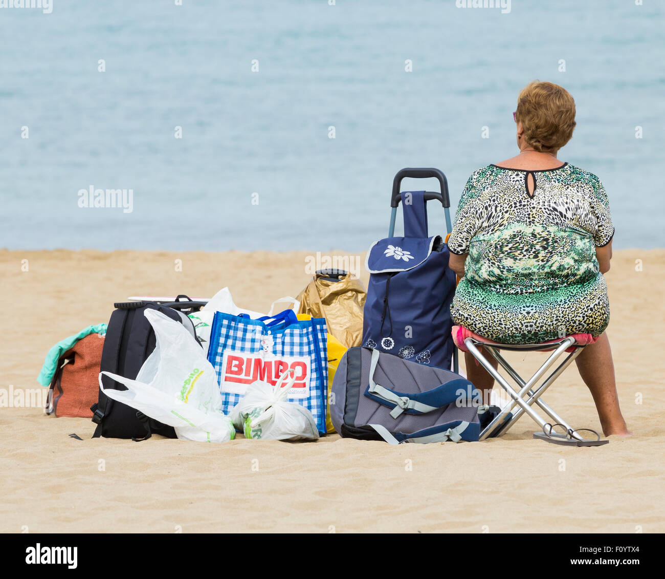 Elderly woman on beach in Spain looking out to sea Stock Photo