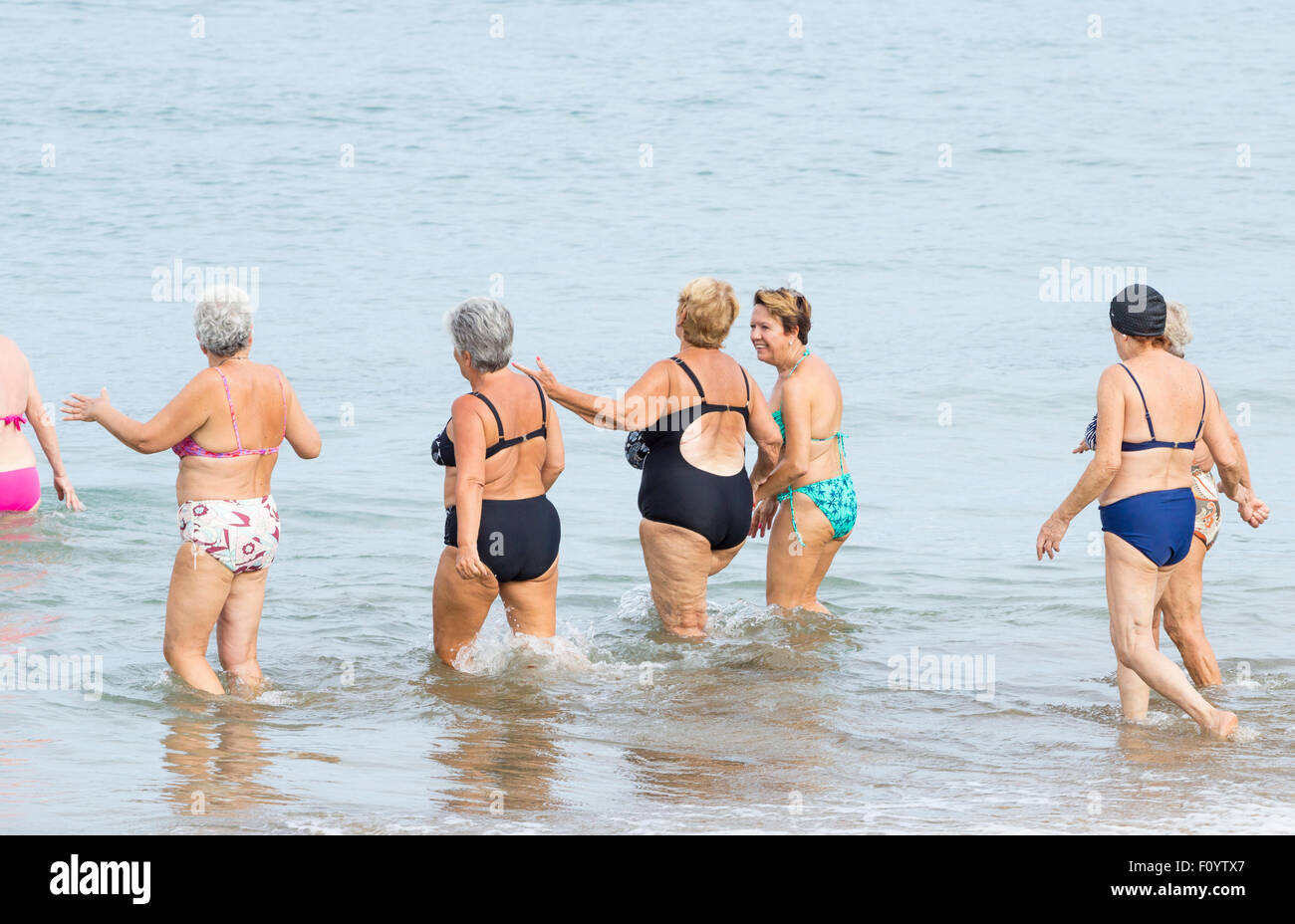 Group of pensioners morning swim following daily keep fit class on beach in Las Palmas, Gran Canaria, Canary Islands, Spain Stock Photo