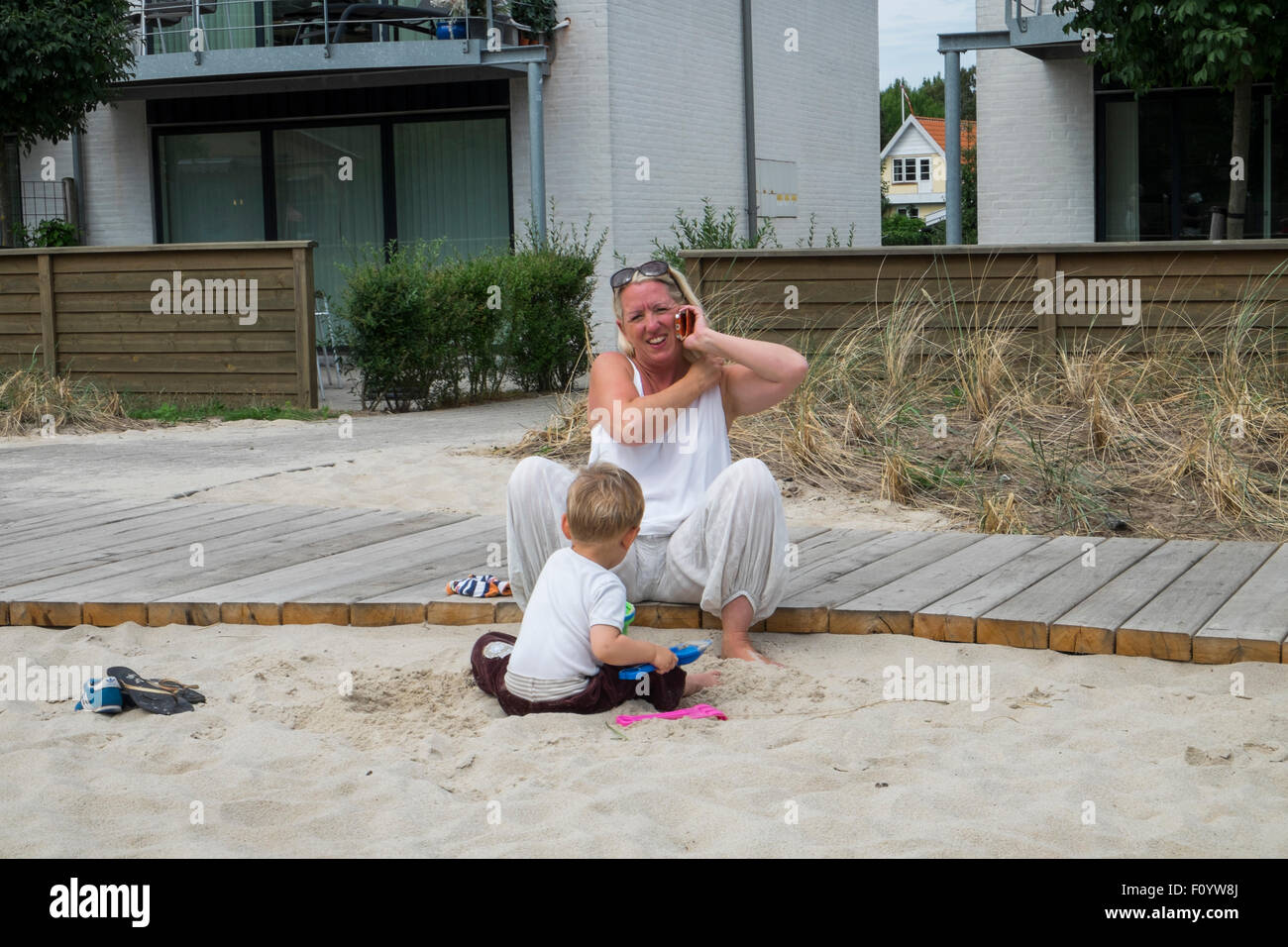 A parent talking on cell phone while she plays with her son Stock Photo