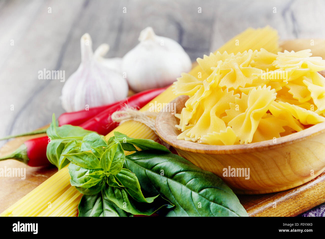Raw spagetti and farfalle pasta on the wooden table Stock Photo
