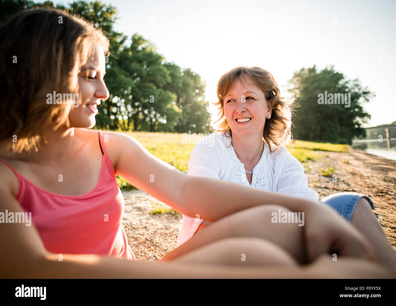 Wide angle photo of teen girl with her mature mother talking together, outdoor in nature Stock Photo