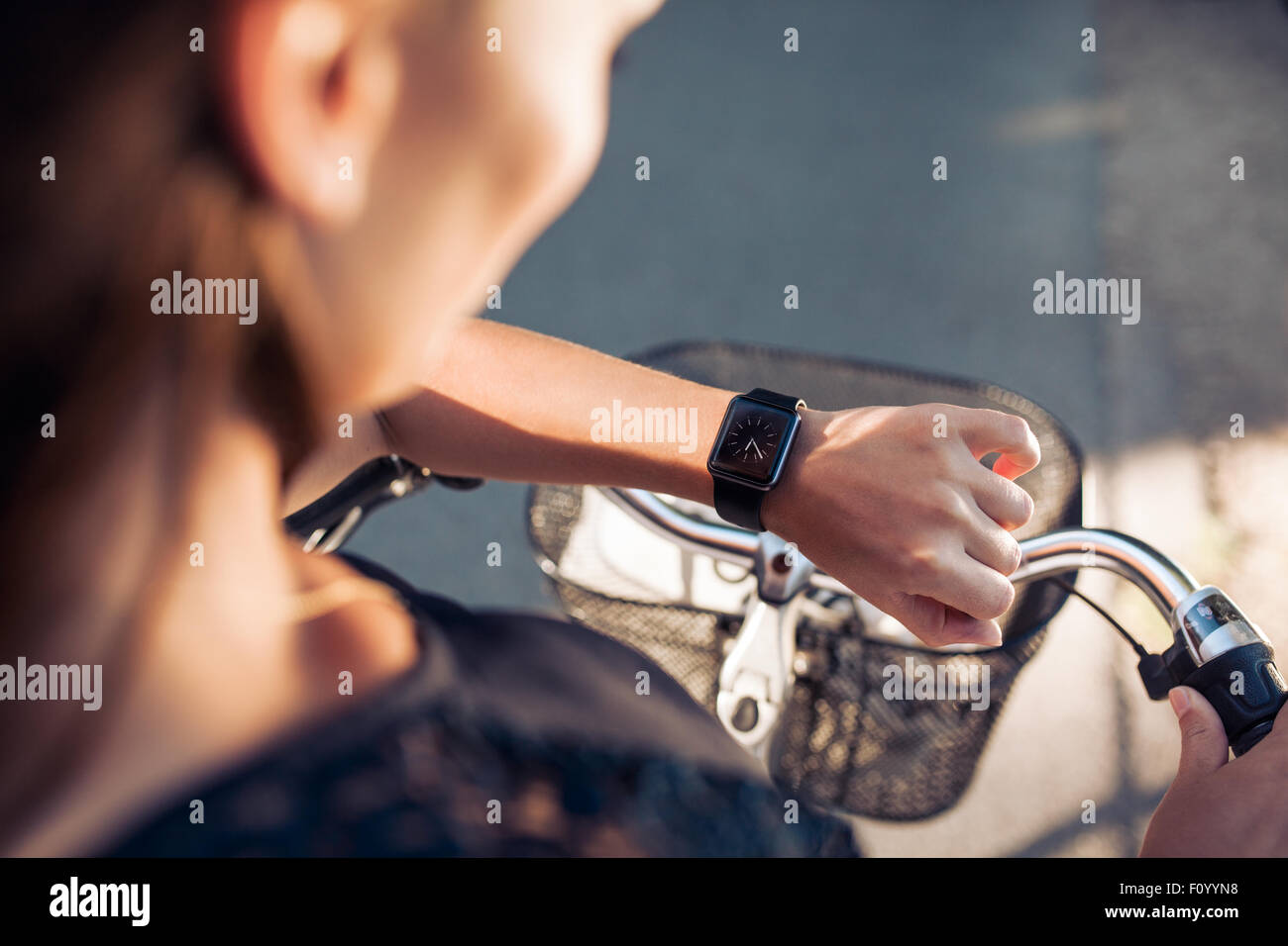 Woman with a bicycle looking at her smartwatch. Close up shot of female checking time on her smart wristwatch. Stock Photo