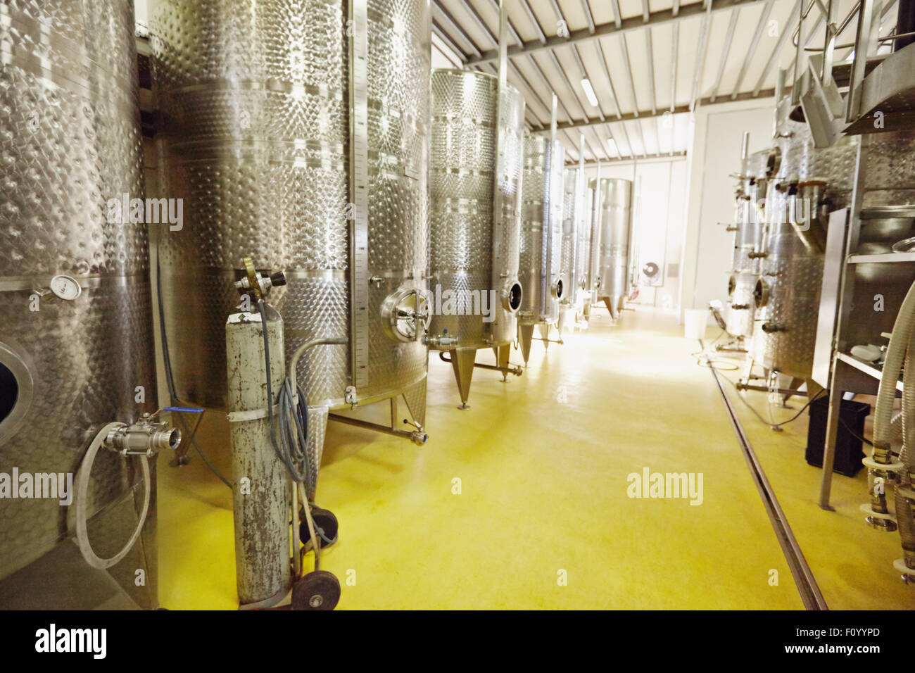 Stainless steel wine vats in a row inside the winery. Equipment of