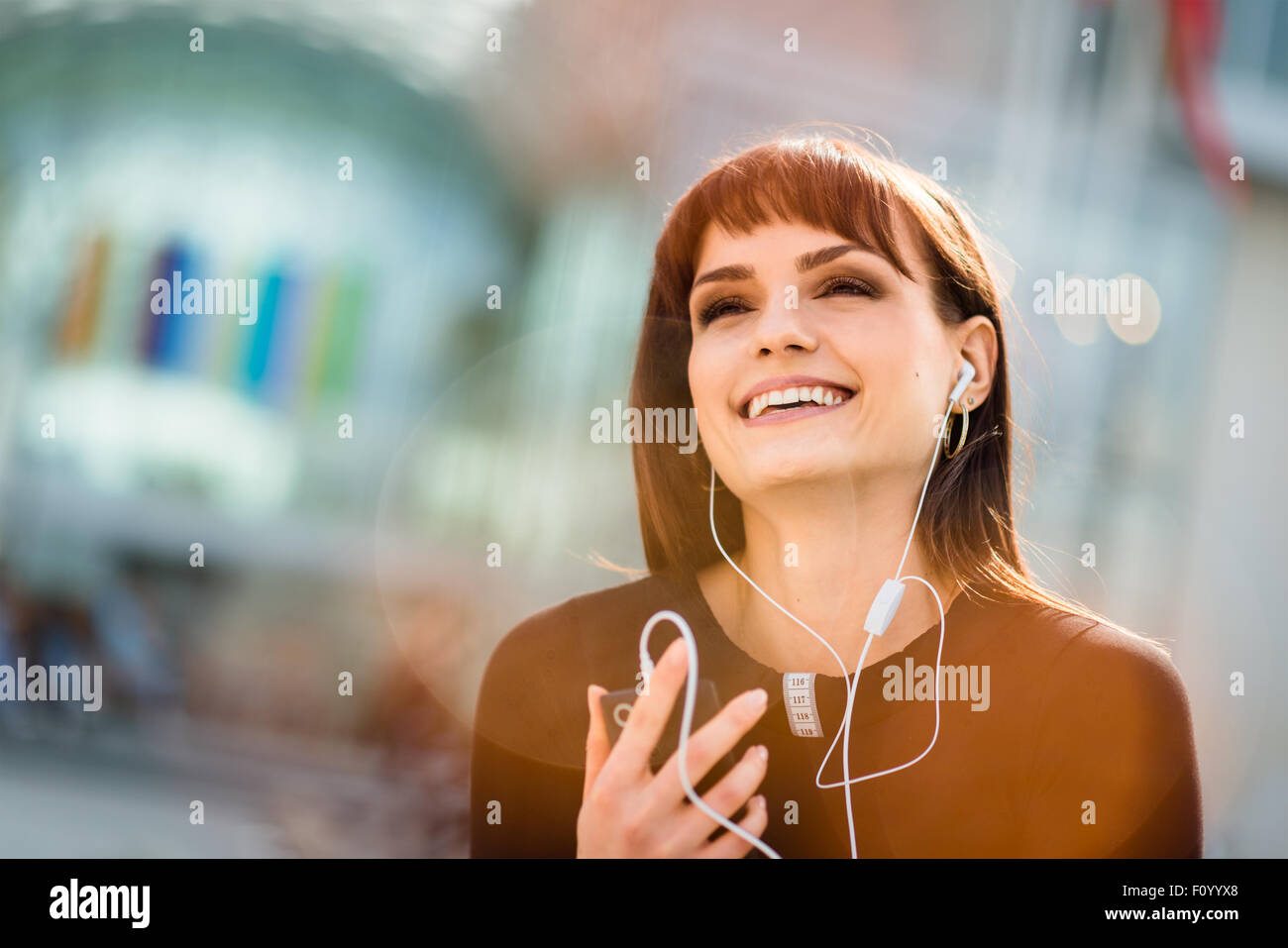 Authentic photo of young woman calling phone with hands free in street Stock Photo