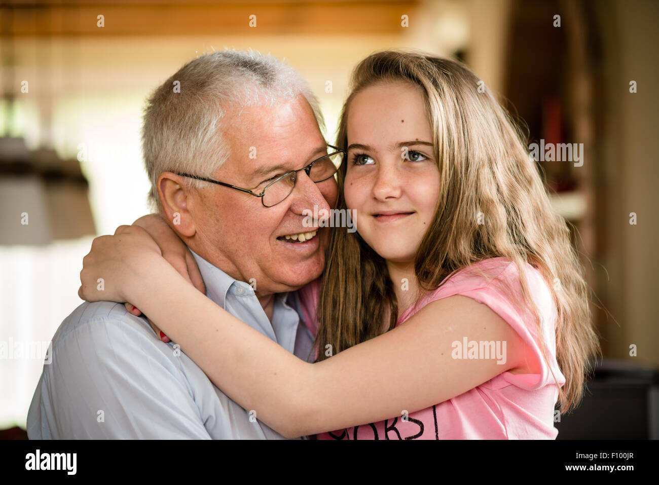 Authentic photo of happy grandfather hugging with his granddaughter indoor at home Stock Photo