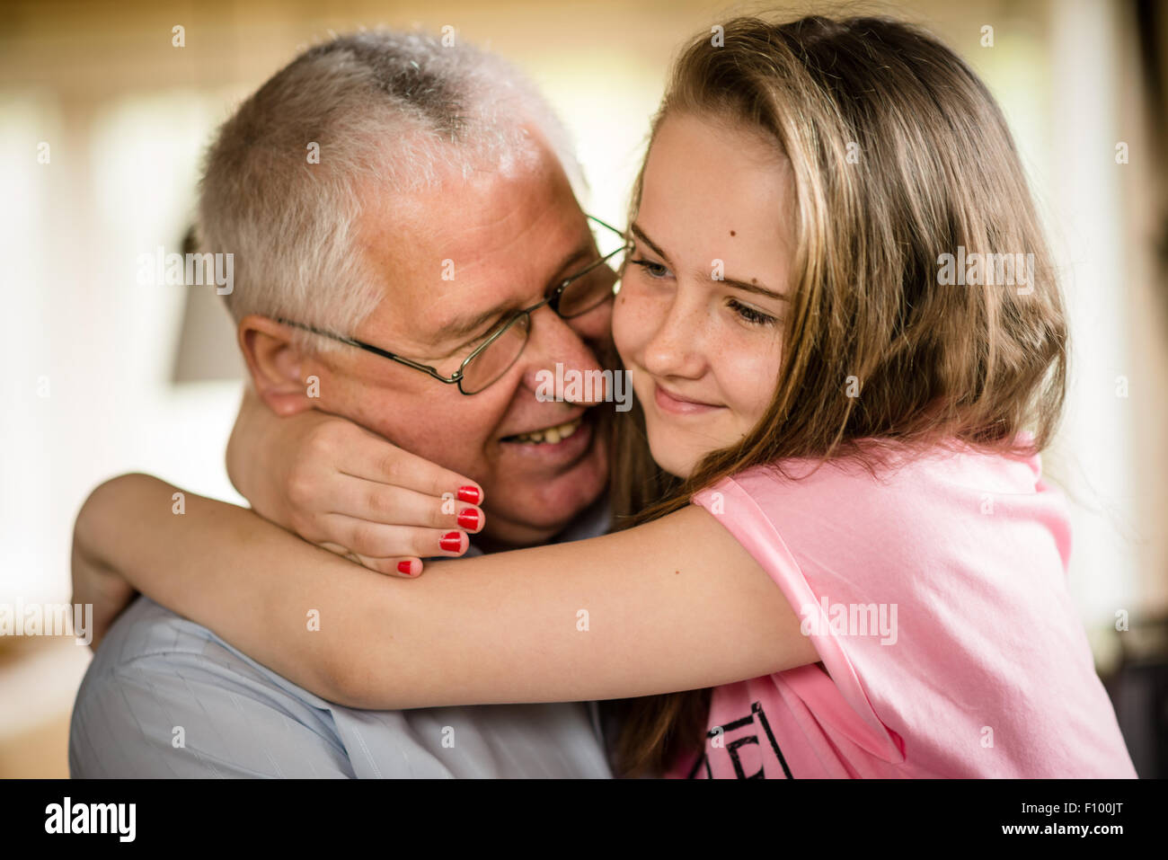 Authentic photo of happy grandfather hugging with his granddaughter indoor at home Stock Photo