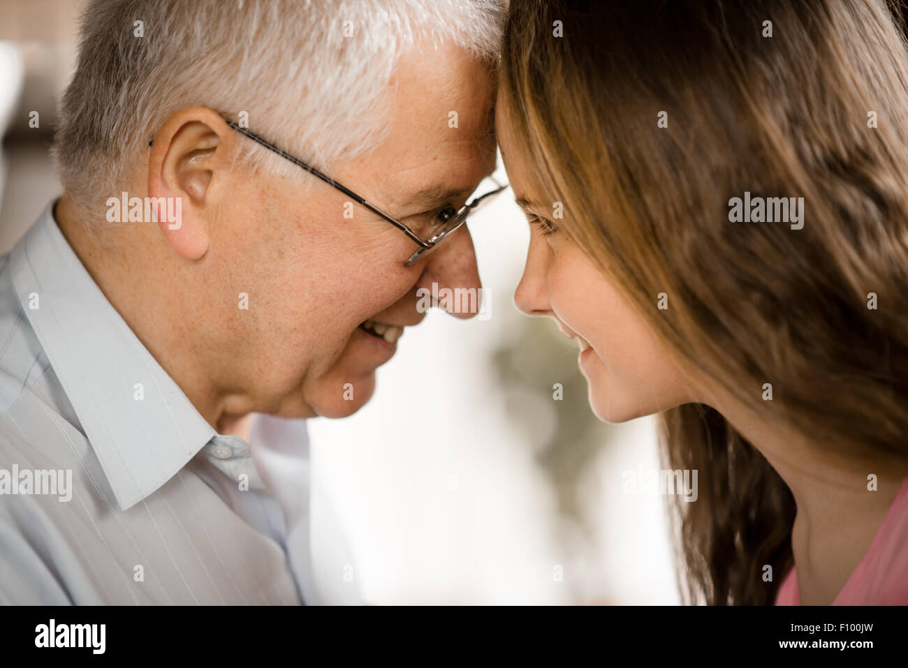 Talking with her grandfather at home with window in background Stock Photo