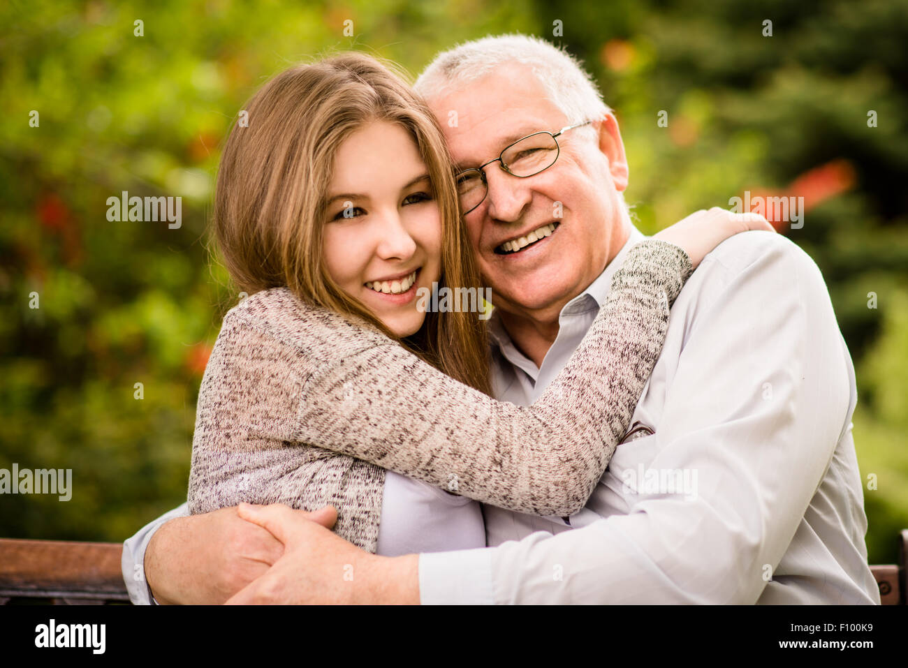 Happy grandfather hugging with his teenage granddaughter outdoor in nature Stock Photo