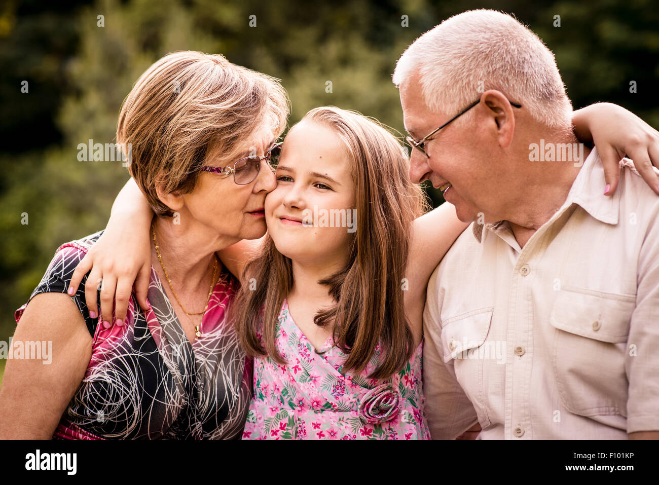 Child embracing her happy grandparents - outdoors in nature Stock Photo