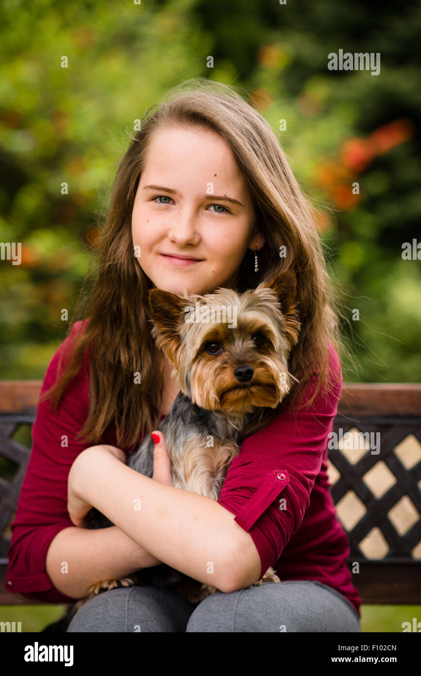 Portrait of girl with her Yorkshire dog sitting on bench outdoor Stock