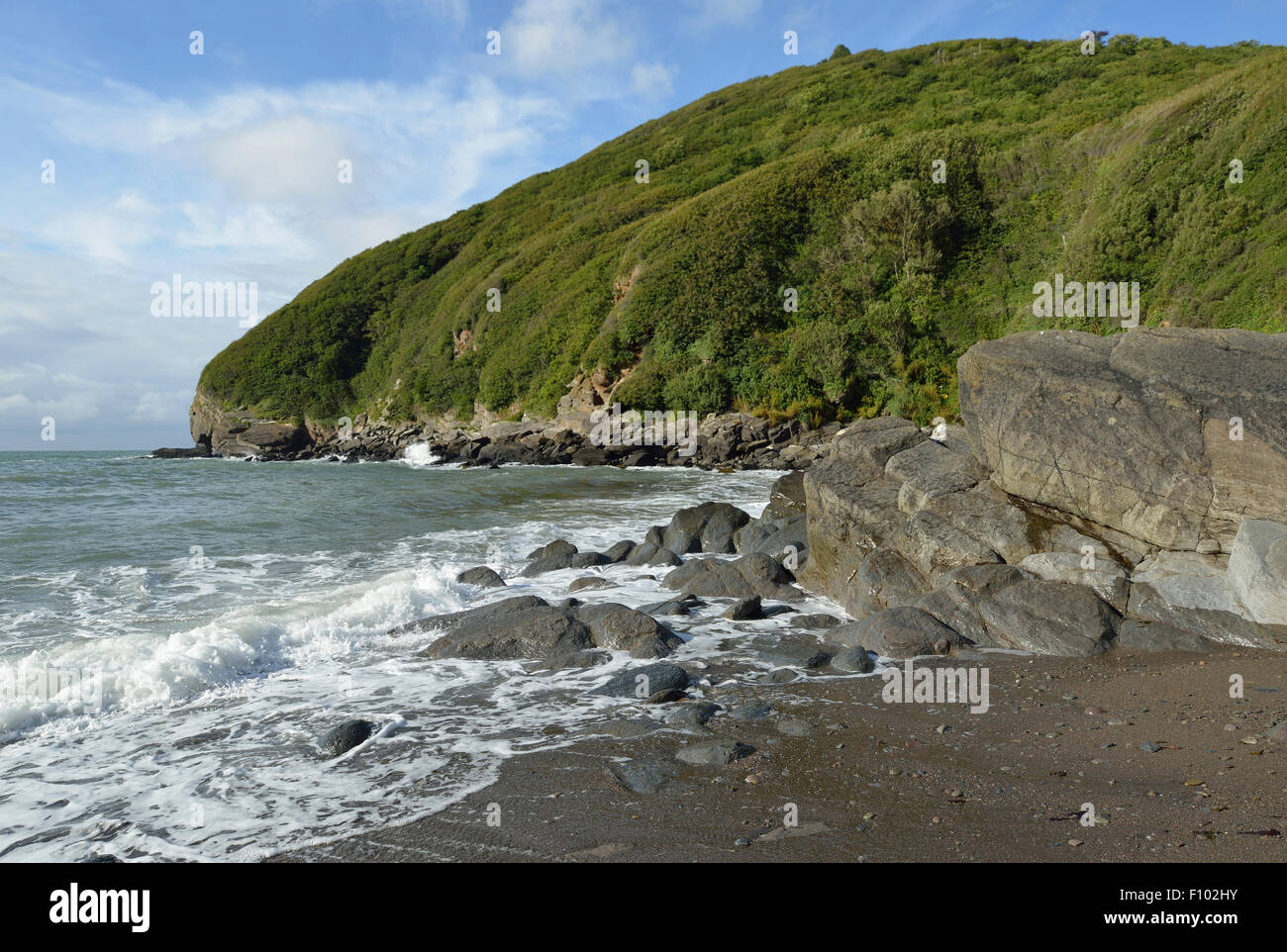 Rocks on Lee Bay Beach with Duty Point behind Stock Photo