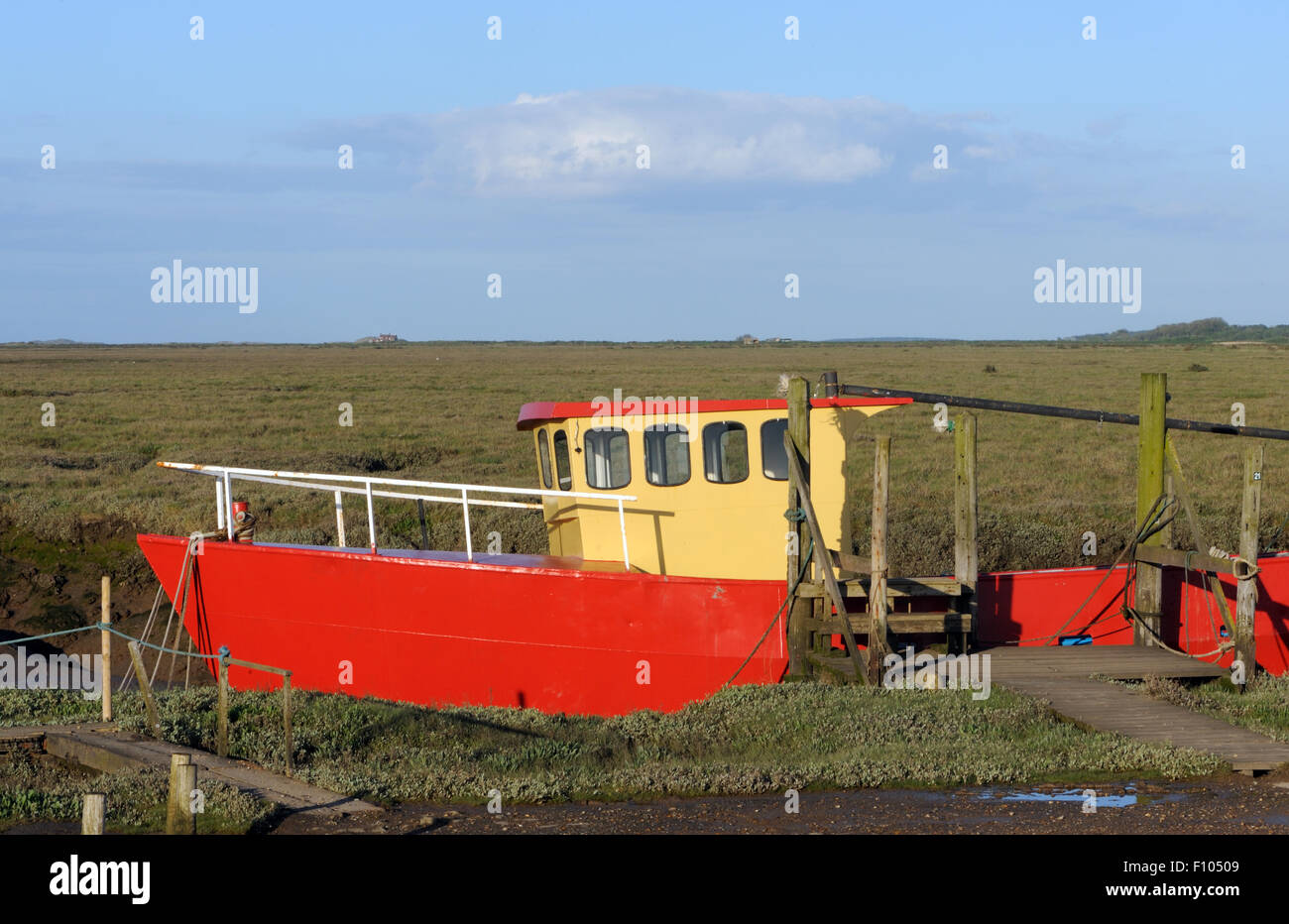 Brown and red boat moored on an inlet of the  River Glaven at Blakeney. Blakeney, Norfolk, UK Stock Photo