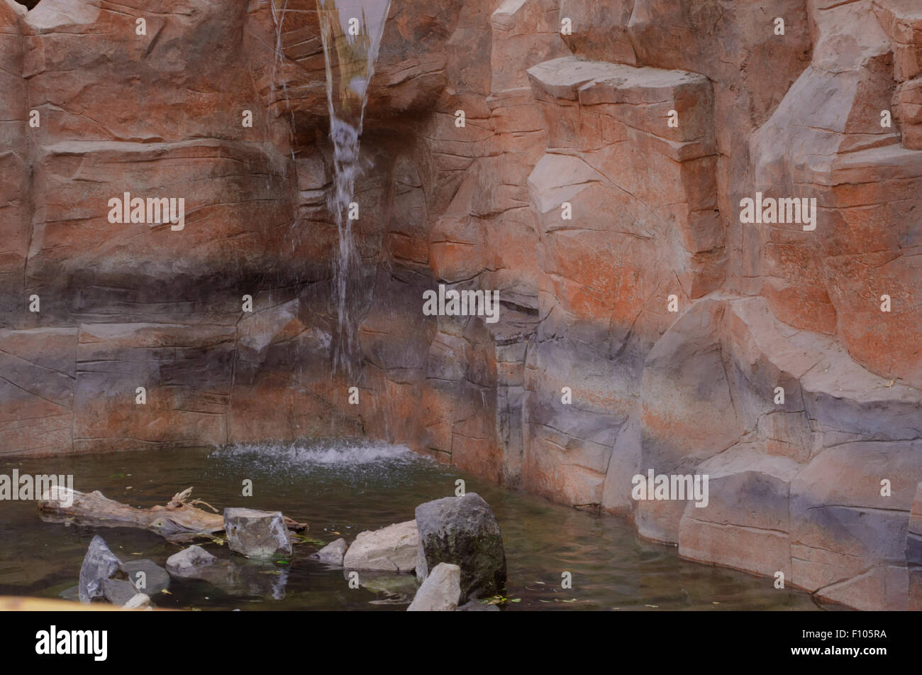 An artificial pond with a waterfall built into the rock Stock Photo
