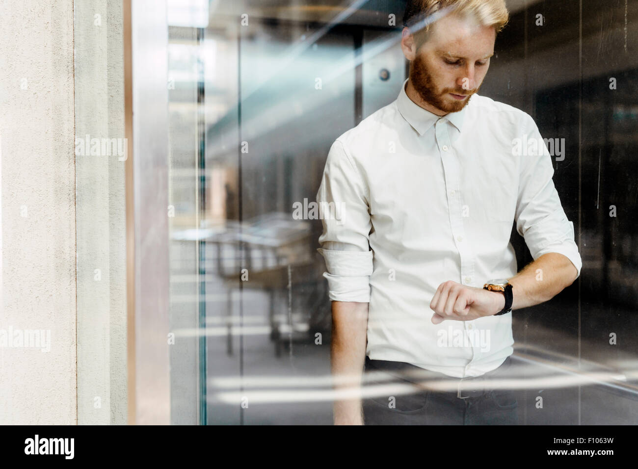 Businessman checking watch while standing in glass covered elevator Stock Photo