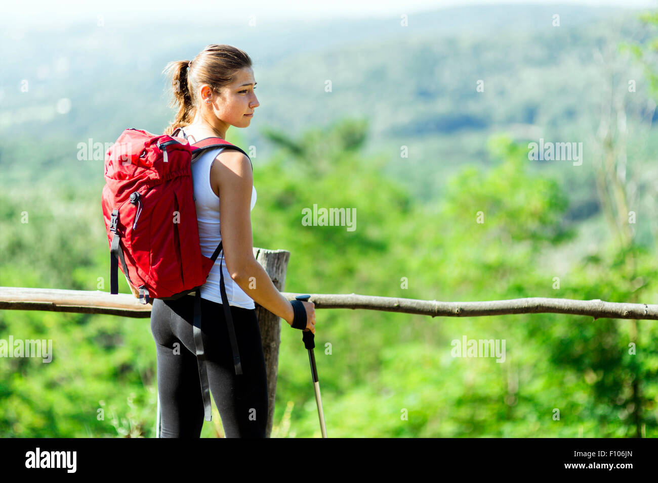 Beautiful hiker woman enjoying the view of a stunning green landscape below her Stock Photo