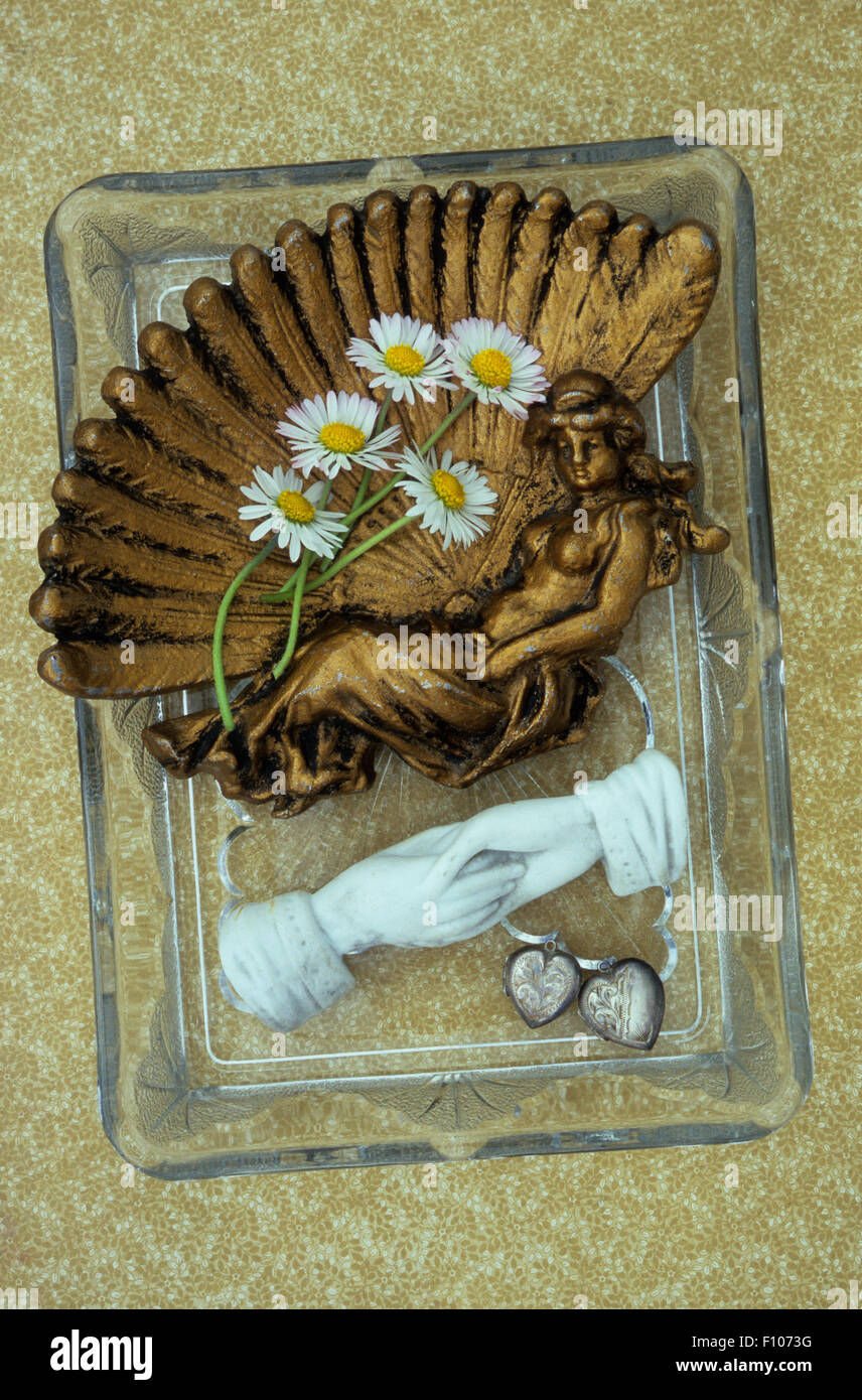 Glass trinket tray with small brass tray  of daisies marble linked hands and two antique silver heart lockets Stock Photo