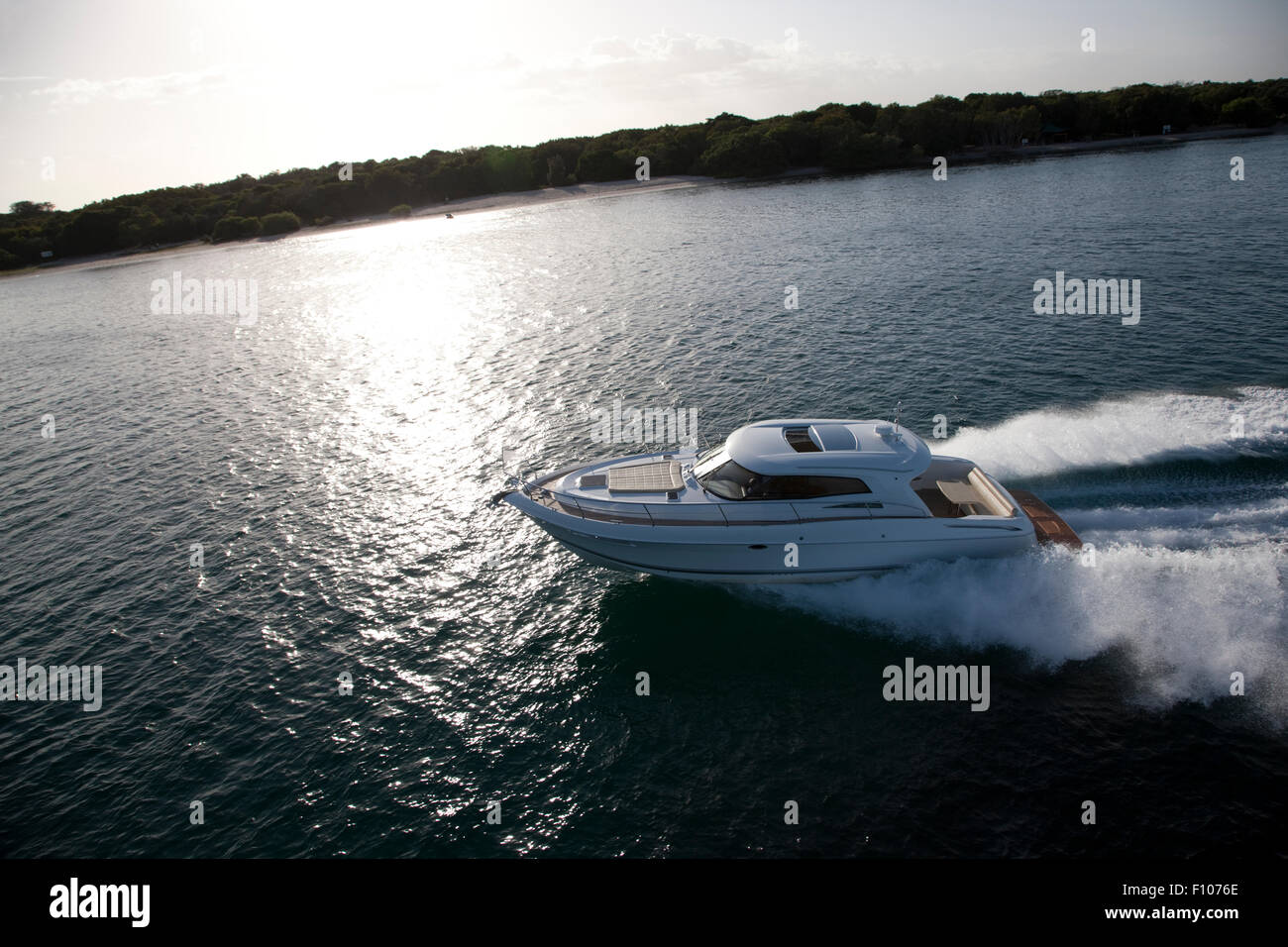 Image of a small motor boat sailing in a sea across a coast on a sunny day Stock Photo