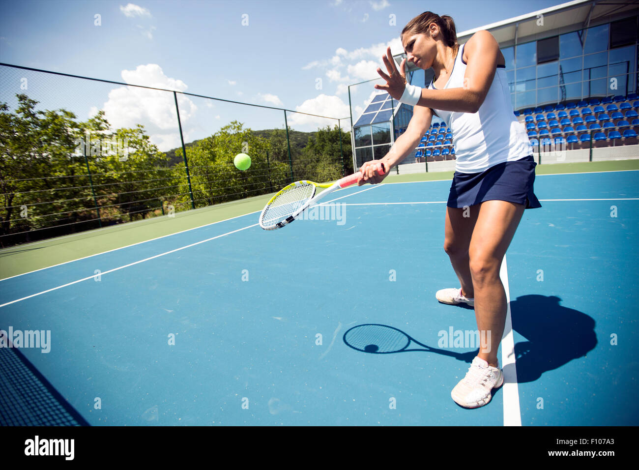 Female tennis player performing a drop shot on a nice blue court Stock Photo