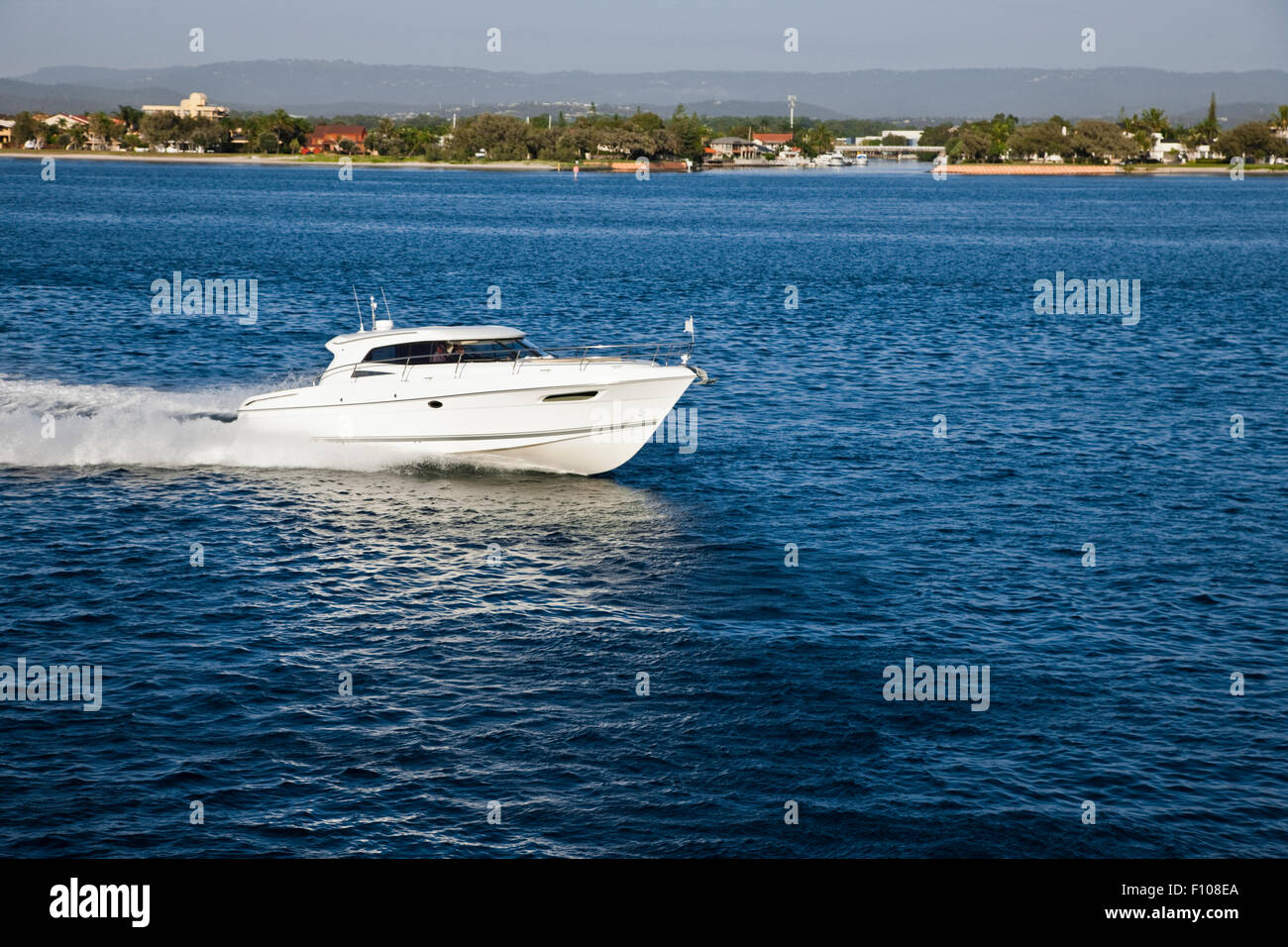 A small motor boat sailing in calm sea close to the coast Stock Photo