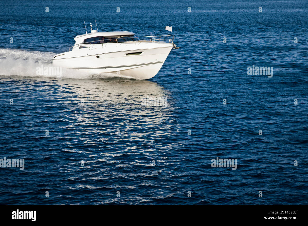 Image of a white motor boat sailing in calm water on a sunny day Stock Photo