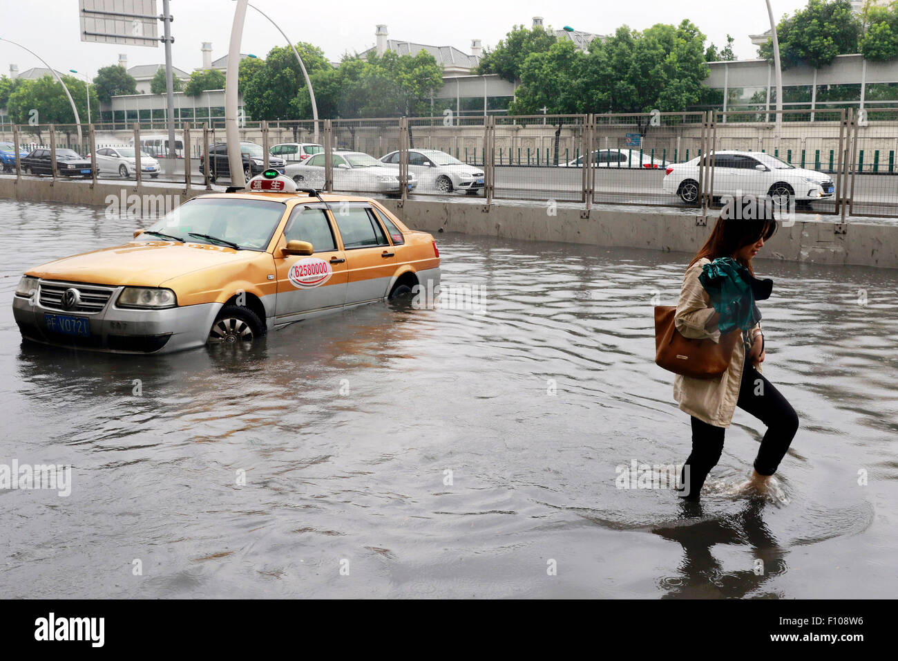 Shanghai. 24th Aug, 2015. A car and a woman are seen on a waterlogged road in east China's Shanghai, Aug. 24, 2015. Shanghai witnessed gales and rainstorms since Sunday night under the influence of the approaching typhoon Swan. Credit:  Zhao Yun/Xinhua/Alamy Live News Stock Photo