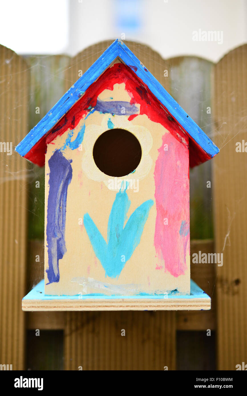 Brightly colored bird house on a fence Stock Photo