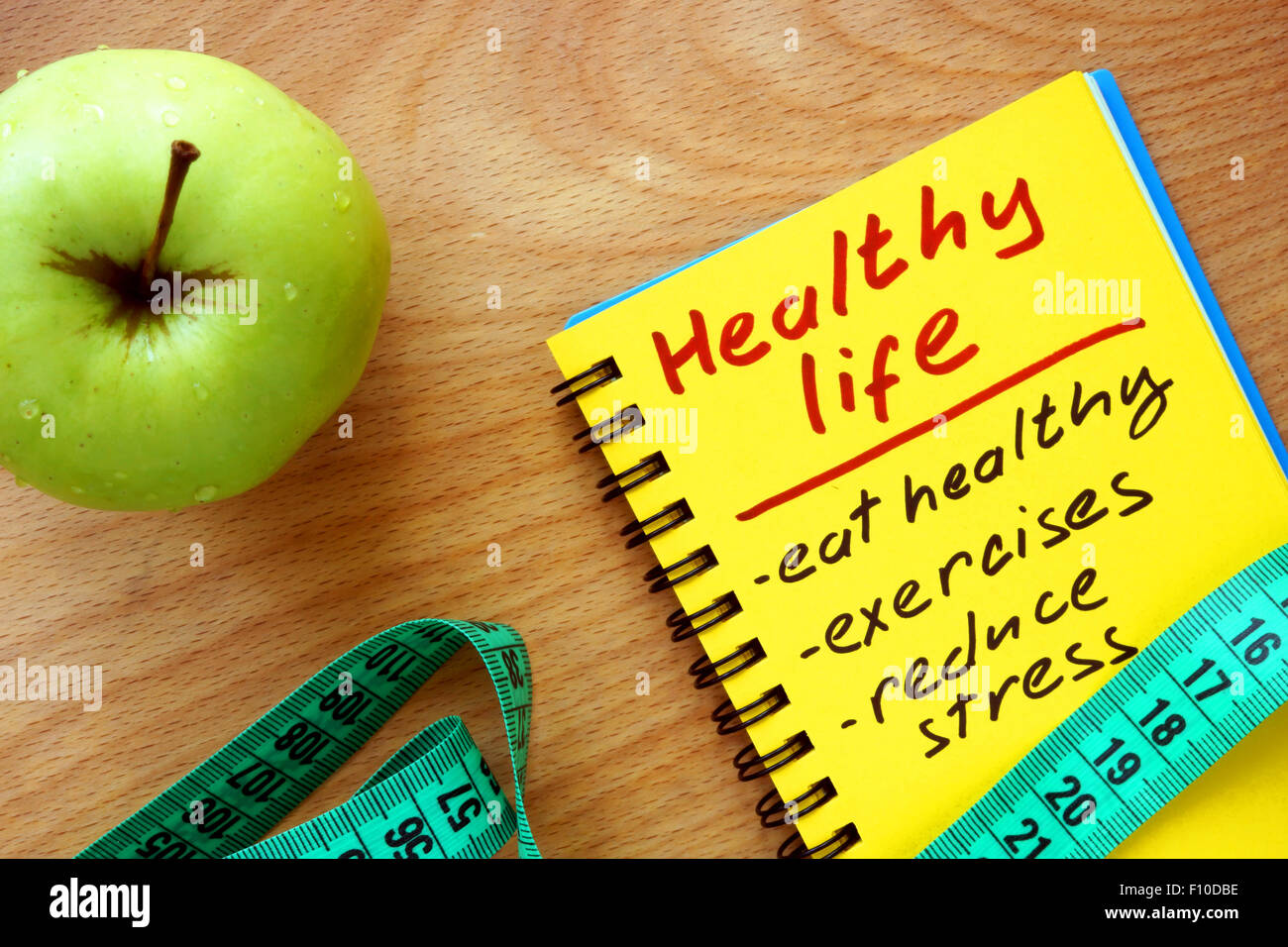 Notepad with healthy life guide, apple and measure tape Stock Photo