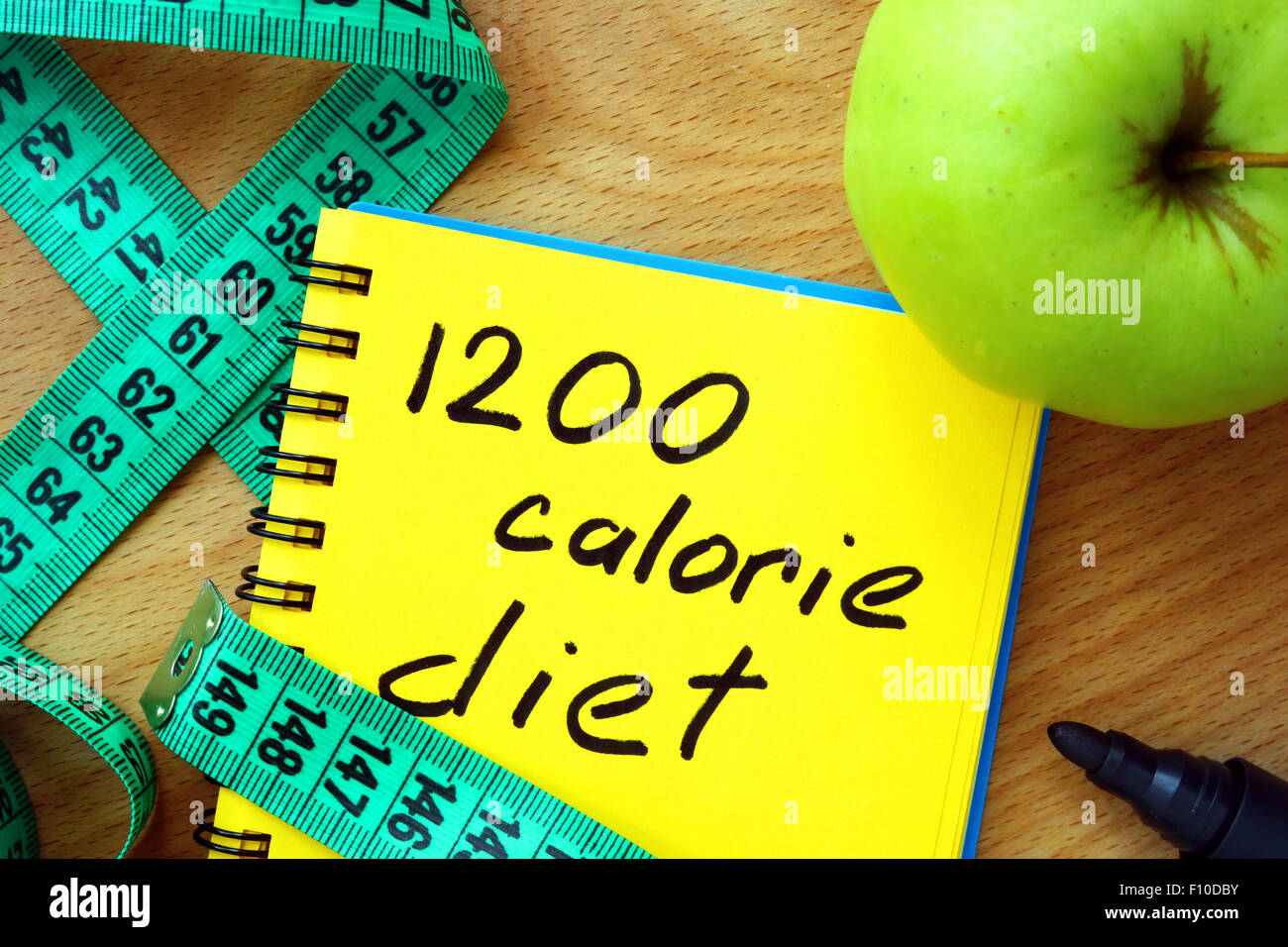 Notepad with 1200 calorie diet, apple and measure tape Stock Photo