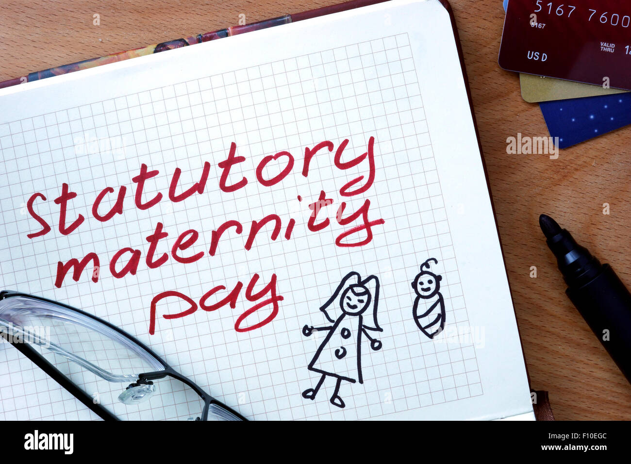 Notepad with statutory maternity pay on office wooden table. Stock Photo