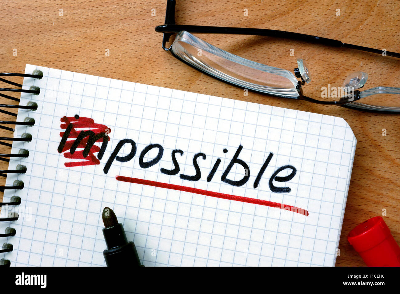 Notepad with  converting the word impossible to possible on office wooden table. Stock Photo