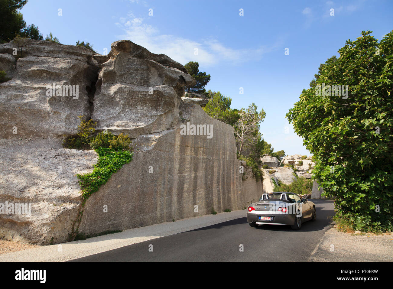 Car on Road  cut through rocky hillside Stock Photo