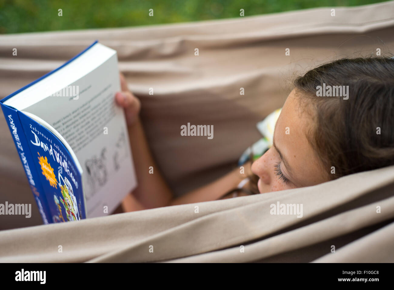 Portrait of Child Girl reading a book in a hammock in the garden ...