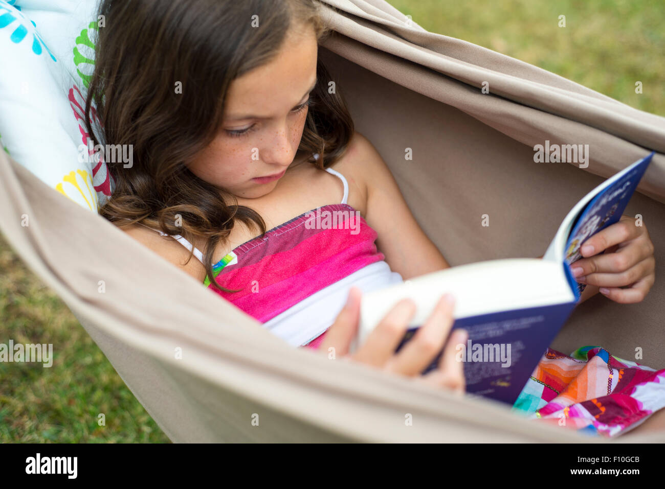 Portrait of Child Girl reading a book in a hammock in the garden ...