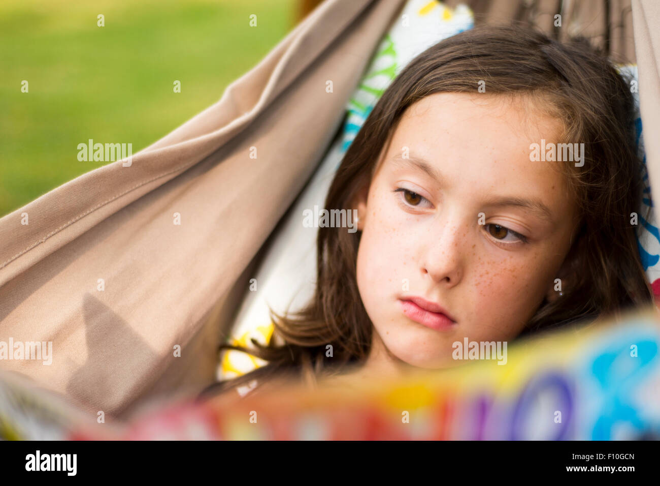 Portrait of Child Girl reading a book in a hammock in the garden ...
