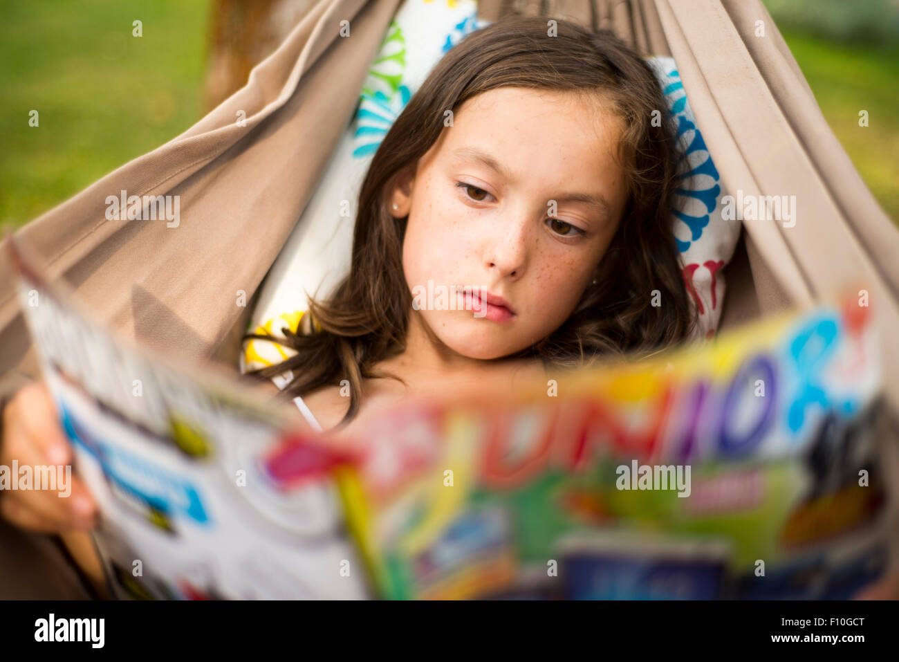 Portrait of Child Girl reading a book in a hammock in the garden ...
